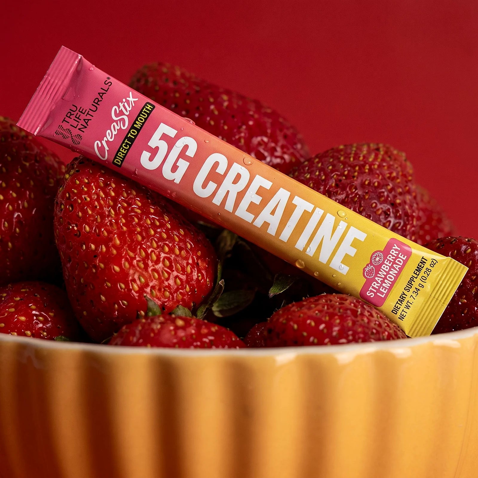 CreaStix Strawberry Lemonade stick resting in a bowl of fresh strawberries