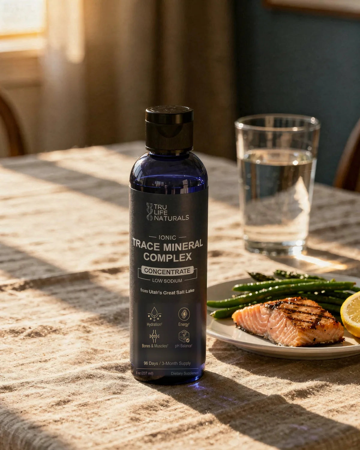 Trace Mineral Complex 8 oz bottle on a dinner table beside a glass of water